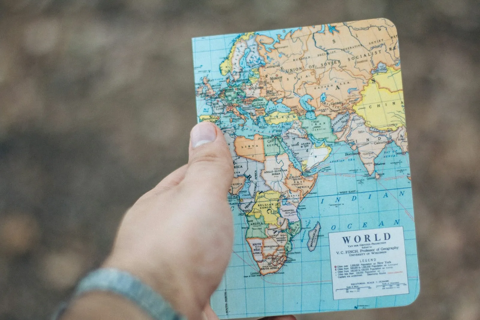 Une main tient une carte du monde dépliée, en plein air
